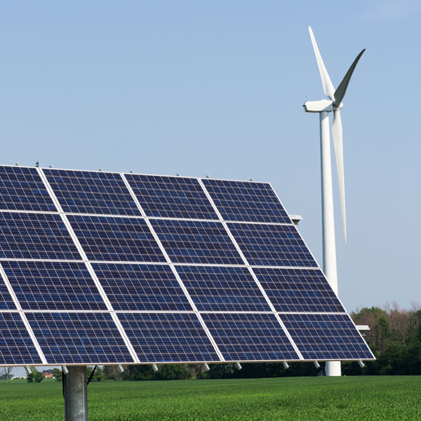 A windmill and solar panel in a grass field